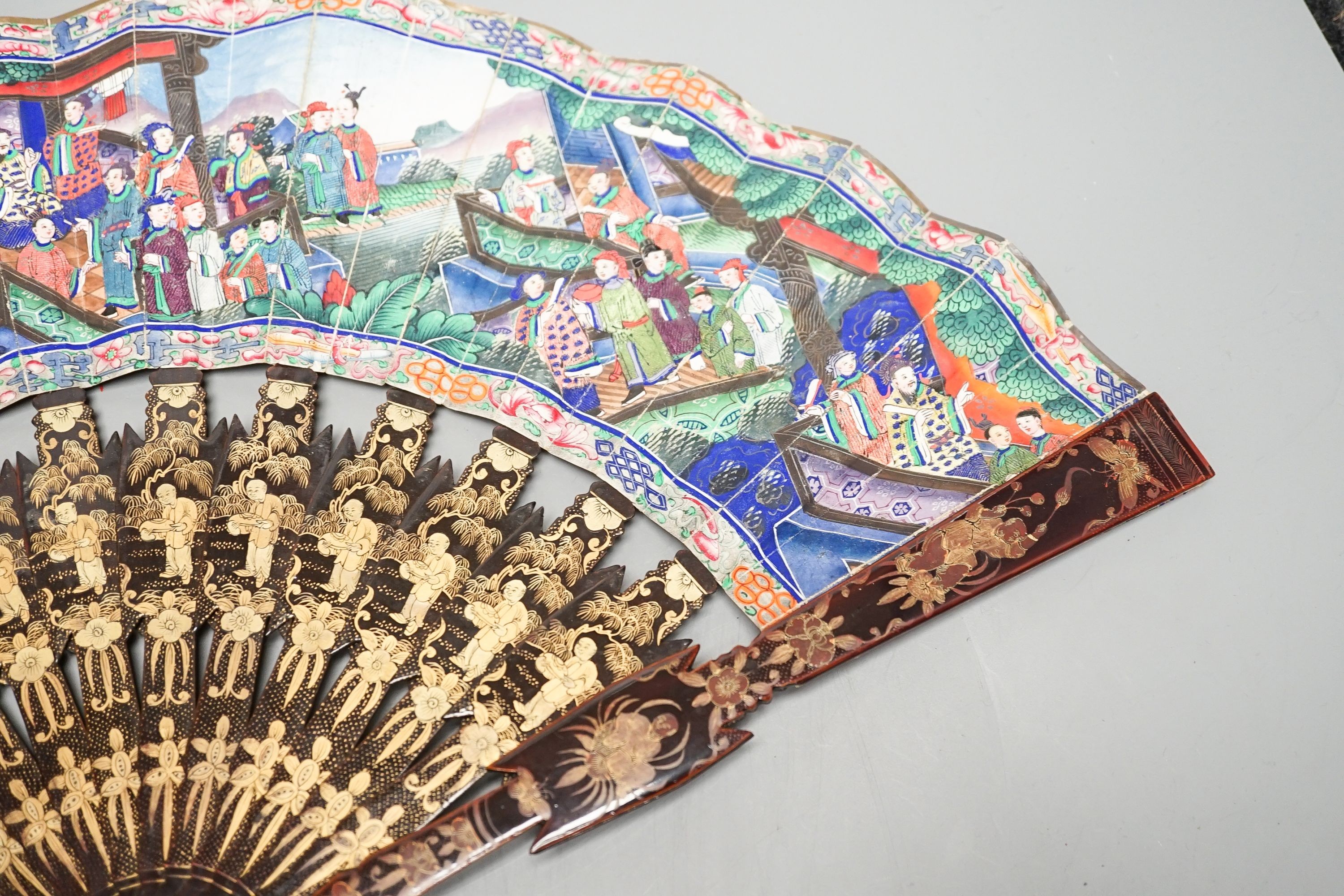 A Chinese export gilt decorated lacquer fan and box, mid 19th century, the appliqué work paper fan leaf decorated with figures amid pavilions and trees, box 32cm